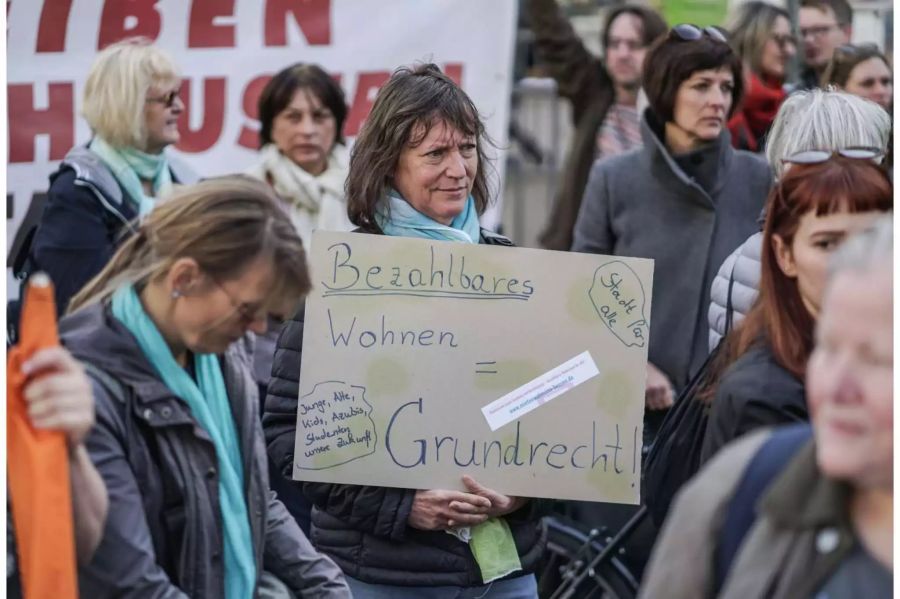 Eine Frau demonstriert im Stadtteil Nordend in Frankfürt am Main für bezahlbaren Wohnraum mit einem Plakat.