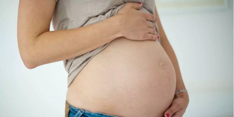 Eine junge Frau hält in Düsseldorf ihren Babybauch.