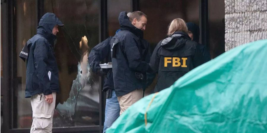 FBI-Beamte checken neben einem mit einer grünen Plane abgedeckten Auto die Einschusslöcher im zerbrochenen Fenster der Tree of Life Synagoge.