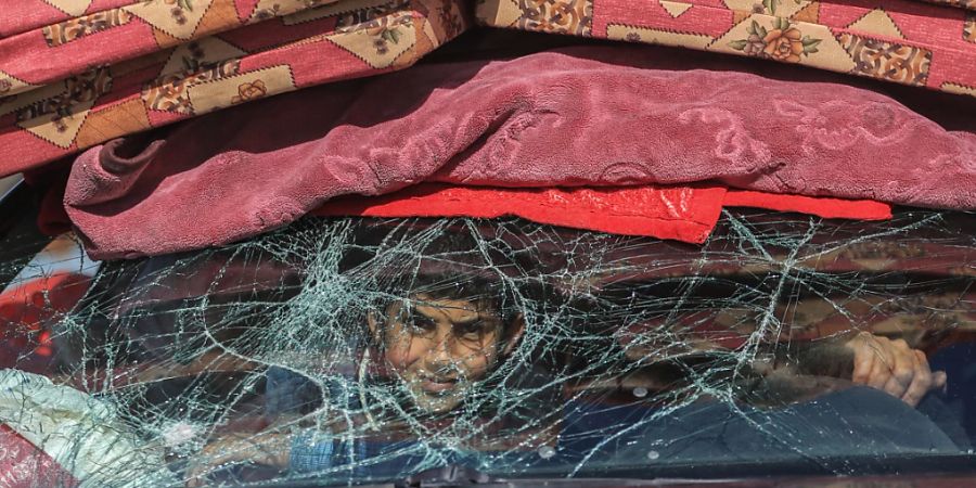 dpatopbilder - Ein Kind schaut aus einem beschädigten Autofenster, während es mit seiner Familie aufgrund israelischer Angriffe auf der Flucht in Richtung Rafah ist. Foto: Mohammed Talatene/dpa