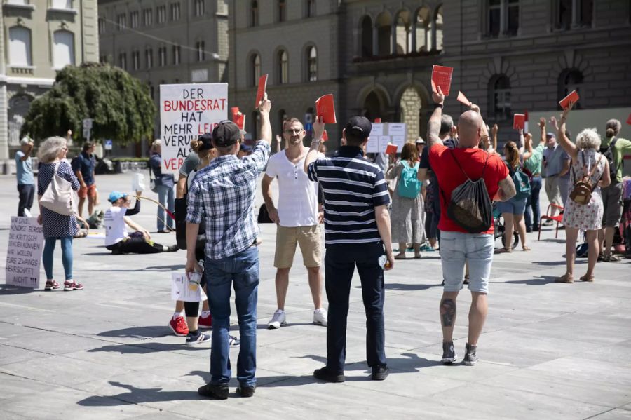 Demonstranten halten ein Exemplar der Schweizer Bundesverfassung hoch, während die Nationalhymne ertönt.