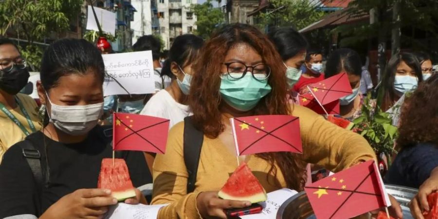 Anti-Putsch-Demonstranten tragen während eines Protests Wassermelonenstücke, in denen durchgestrichene chinesische Fähnchen stecken. Foto: --/AP/dpa