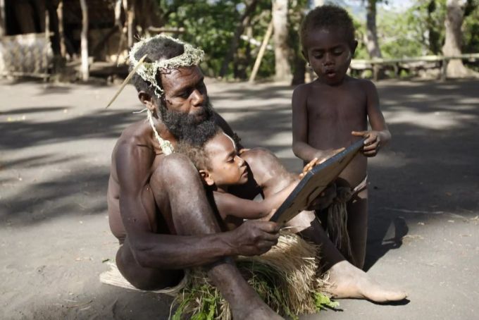 Ein Vater auf Tana zeigt seinen Kindern ein gerahmtes Bild von Prinz Philip. Prinz Philip Vanuatu