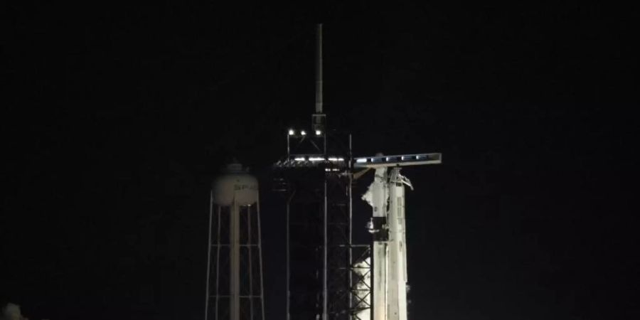 Eine Falcon-9-Trägerrakete mit dem «Crew Dragon» während eines kurzen Feuertests. Foto: Joel Kowsky/NASA via AP/dpa