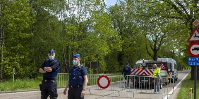 Belgische Polizisten sperren eine Strasse in einem Waldstück ab. Leichenfund