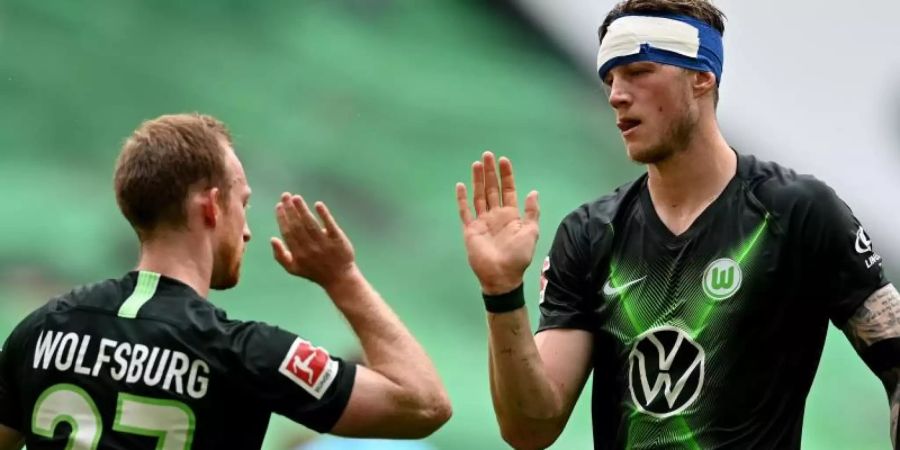 Wolfsburgs Stürmer Weghorst (r), der einen Verband am Kopf trägt, bejubelt einen Treffer mit Mannschaftskamerad Arnold. Foto: Sascha Steinbach/epa Pool/dpa