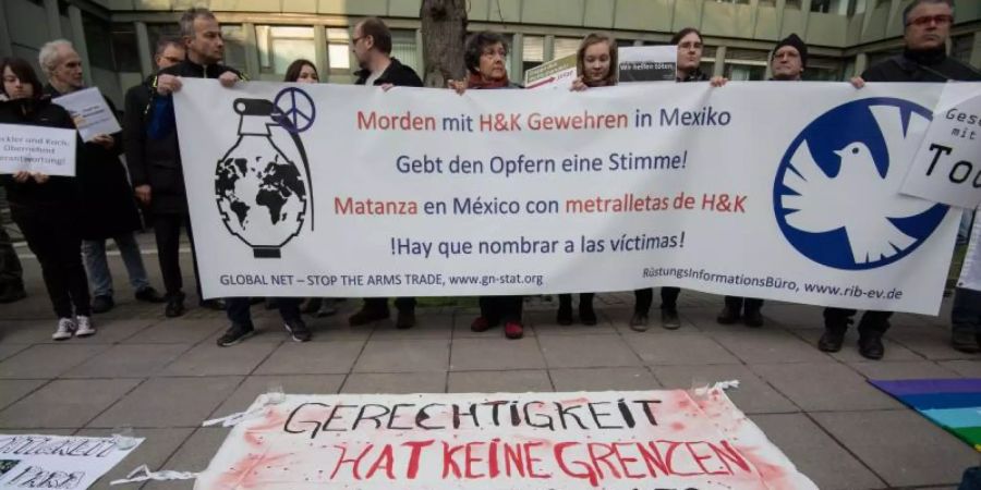 Demonstranten stehen vor der Urteilsverkündung im Prozess gegen ehemalige Mitarbeiter von Heckler und Koch mit einem Transparent vor dem Landgericht Stuttgart. Foto: Marijan Murat/dpa