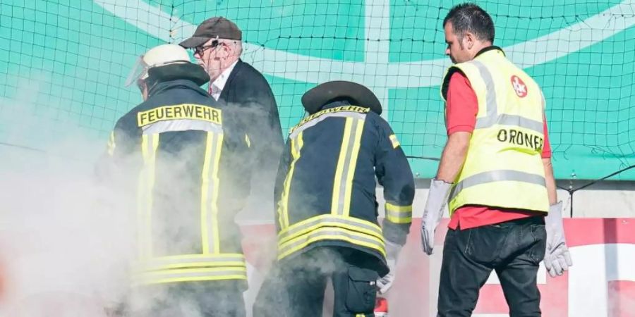 Feuerwehrleute löschen Bengalos aus dem Mainzer Fanblock. Foto: Uwe Anspach