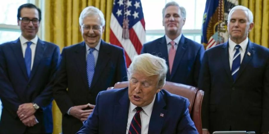 US-Präsident Donald Trump unterzeichnet das Coronavirus-Konjunkturpaket. Foto: Evan Vucci/AP/dpa