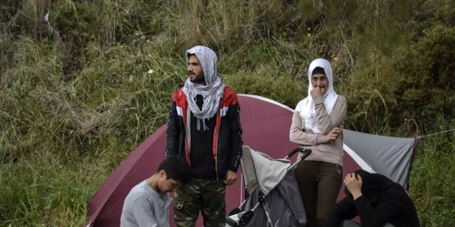 Migranten ruhen vor einem Zelt im Dorf Petra auf der nordöstlichen Ägäisinsel Lesbos in Griechenland. Foto: Panagiotis Balaskas/AP/dpa