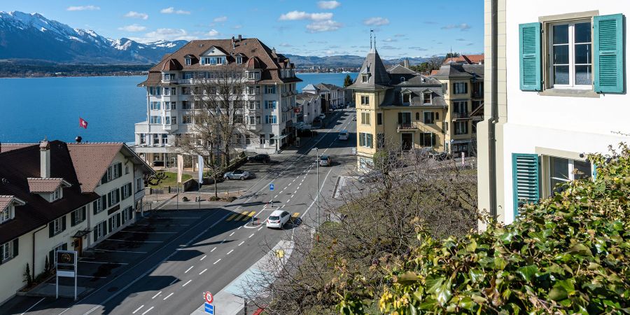 Blick von der Kirche Hilterfingen auf das Hotel Bellevue au Lac, die Staatsstrasse und den Thunersee.