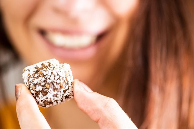 Aus Datteln, Nüssen und Kokosraspeln sind rasch süsse Snacks hergestellt. Auch sie finden in einer rohköstlichen Ernährung Platz. Datteln Energyball Kokos Frau