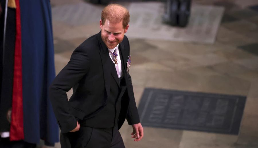 Prinz Harry lächelt in der Westminster Abbey bei der Krönung seines Vaters.