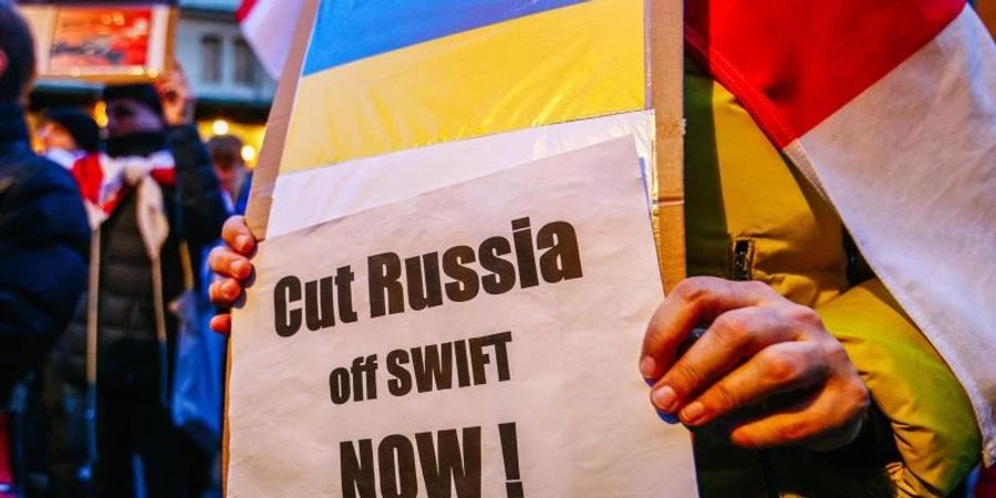 Ein Demonstrant hält ein Schild mit der ukrainischen Flagge und der Aufschrift «Russland jetzt abschneiden!». Foto: Filip Radwanski/SOPA Images via ZUMA Press Wire/dpa