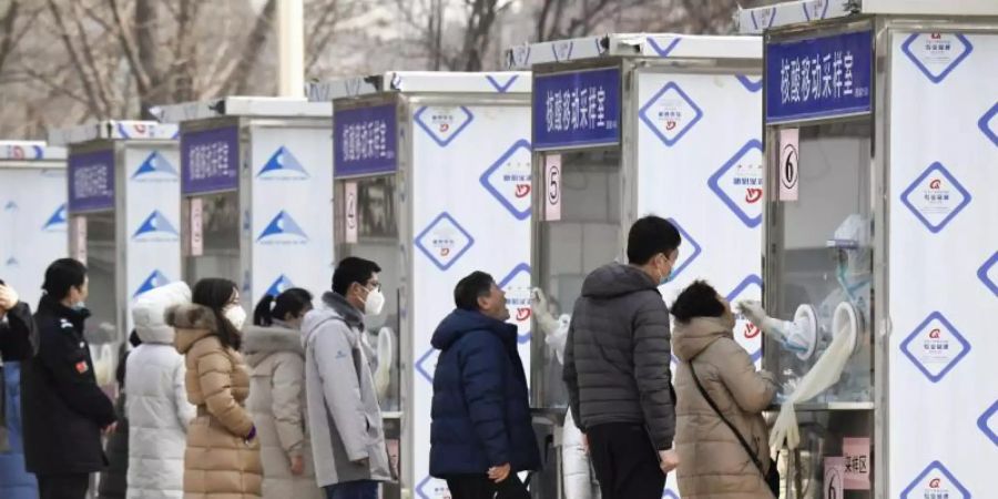 Menschen warten im Pekinger Stadtbezirk Xicheng im Rahmen eines Corona-Massentests vor Test-Kabinen. Foto: -/kyodo/dpa