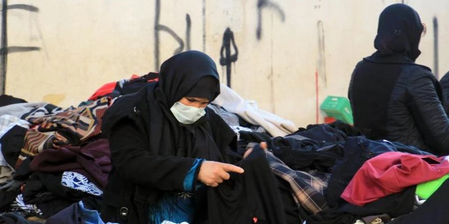 Eine Kundin schaut sich gebrauchte Kleidungsstücke auf einem zentralen Markt in Tunesiens Hauptstadt an. Foto: Cindy Riechau/dpa