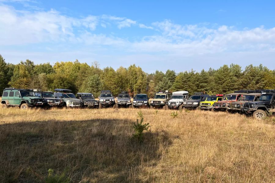 Geländewagen im Halbkreis auf trockener Wiese