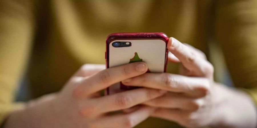 Eine junge Frau hält ein Smartphone in der Hand. Verbraucher in der EU werden weitere zehn Jahre vom Wegfall der Roaming-Gebühren profitieren. Foto: Fabian Sommer/dpa