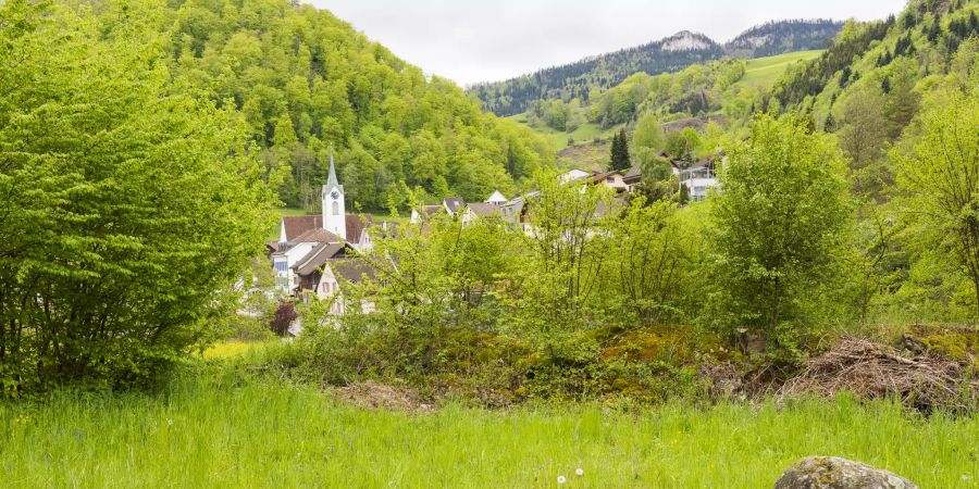 Blick auf den Dorfkern Eptingen mit der reformierten Kirche und der Belchenfluh im Hintergrund.