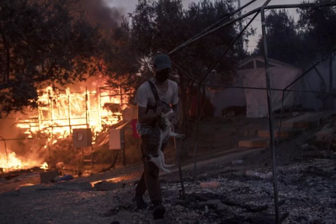 Ein Mann rettet eine Katze und sich selbst vor den Flammen in Moria. Moria Spenden Lesbos Feuer