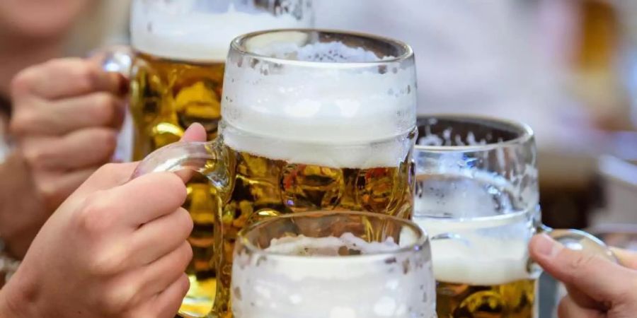 Besucher stossen auf dem Oktoberfest mit Bier an. Im ersten Halbjahr wurde 6,6 Prozent oder gut 300 Millionen Liter weniger Bier getrunken als im ohnehin schwachen Vorjahr. Foto: Matthias Balk/dpa
