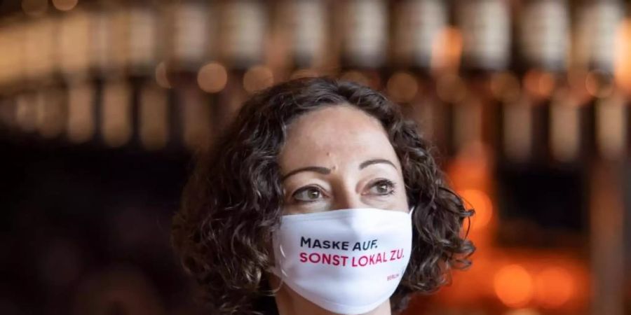 Maske trägt längst nicht jeder. Mit Sprüchen auf Plakaten, Bierdeckeln und Masken sollen Gäste in Berlin an die Corona-Schutzmassnahmen erinnert werden. Foto: Bernd von Jutrczenka/dpa