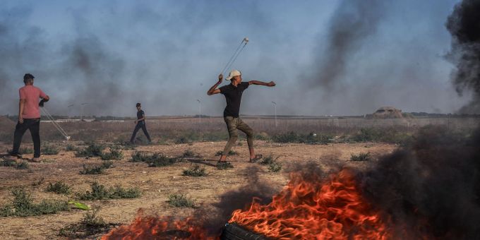 Ein palästinensischer Jugendlicher schleudert in Richtung israelischer Truppen. Ein palästinensischer Jugendlicher schleudert in Richtung israelischer Truppen.