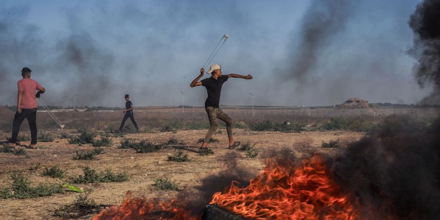 Ein palästinensischer Jugendlicher schleudert in Richtung israelischer Truppen.