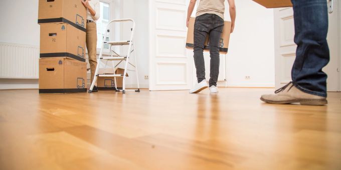 Ein junger Mann, eine ältere Frau und ein älterer Mann tragen Umzugskartons in eine Wohnung. umzug