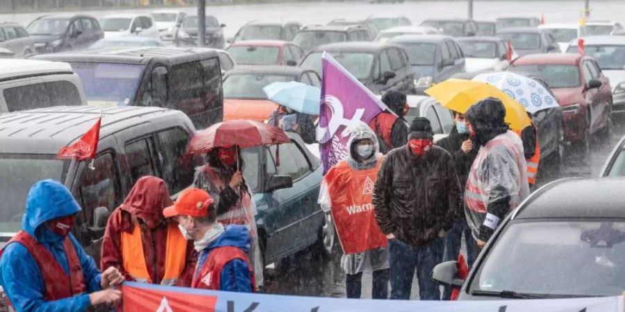 In strömendem Regen stehen Mitarbeiter am Stammsitz des Autobauers Opel oder sitzen in ihren Fahrzeugen, um gegen zunehmenden Druck an ihren Arbeitsplätzen zu demonstrieren. Foto: Frank Rumpenhorst/dpa