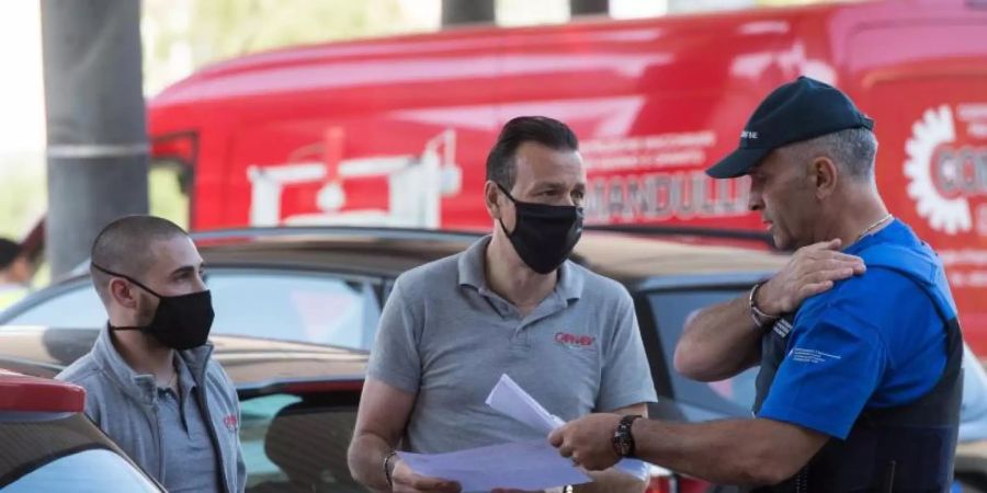 Zwei Männer sprechen am Grenzübergang mit einem Grenzbeamten und zeigen Dokumente vor. Foto: Alessandro Crinari/KEYSTONE/Ti-Press/dpa