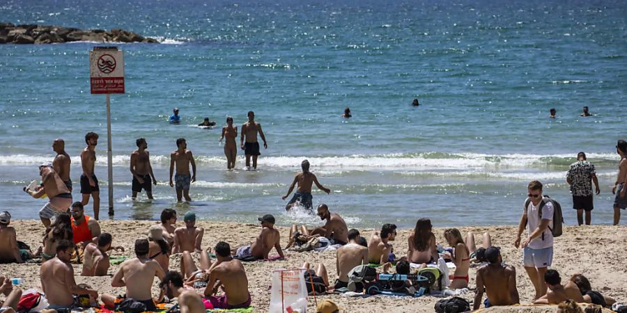 Menschen verbringen den Tag in der Sonne am Strand in Tel Aviv. Durch die fortgeschrittene Impfkampagne in Israel werden die Corona-Massnahmen immer weiter aufgehoben. Foto: Ilia Yefimovich/dpa