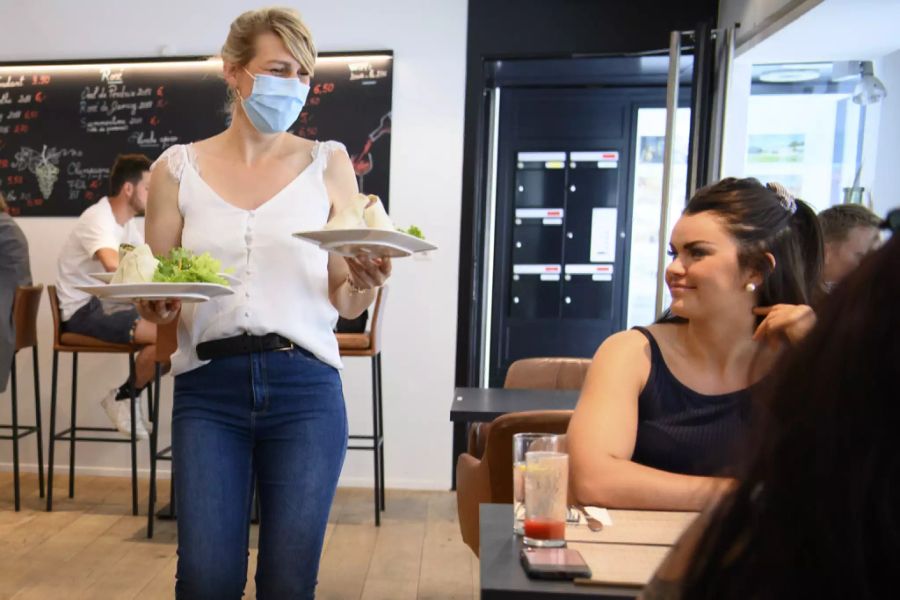 Eine Service-Angestellte bringt Gästen in Porrentruy JU ihr Essen – drinnen.