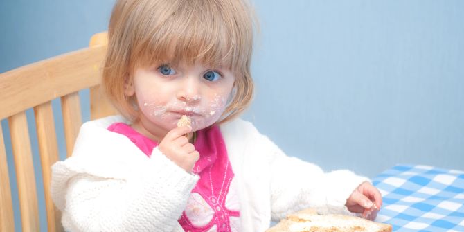 Kleines Mädchen isst Toast mit Butter
