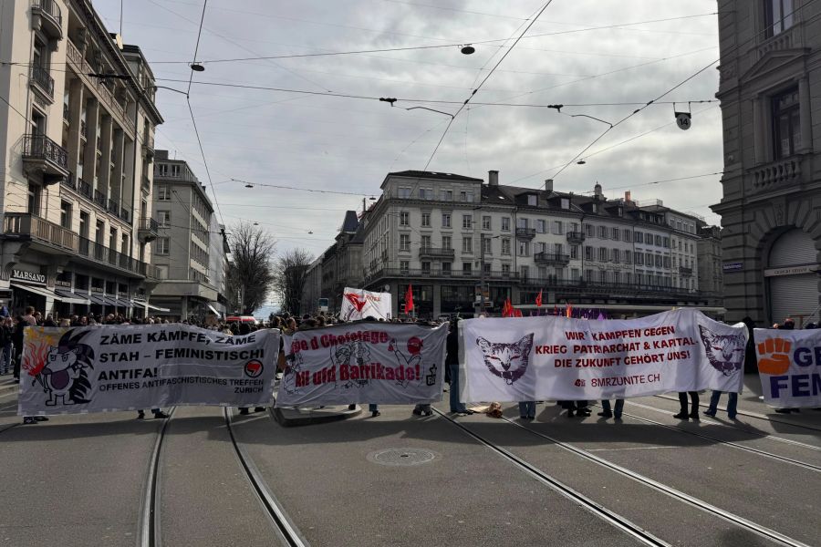 Teilnehmende halten verschiedene Banner hoch.