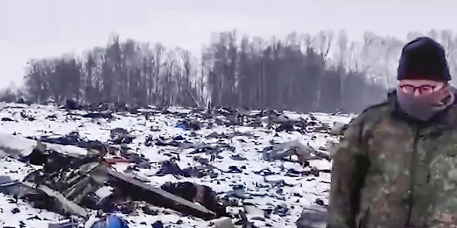 HANDOUT - Ein Mitarbeiter des Russischen Ermittlungskomitees geht in der Nähe von Jablonowo in der Region Belgorod durch ein Gebiet, in dem Wrackteile der russischen Militärmaschine Il-76 abgestürzt sind. Die Ukraine hält die von Russland zum mutmasslichen Abschuss der militärischen Transportmaschine Il-76 bisher vorgelegten Angaben für nicht stichhaltig. Foto: Uncredited/Russian Investigative Committee/AP/dpa