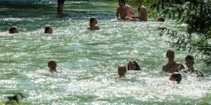 Menschen erfrischen sich im Eisbach im Englischen Garten in München. Foto: Peter Kneffel Menschen erfrischen sich im Eisbach im Englischen Garten in München. Foto: Peter Kneffel