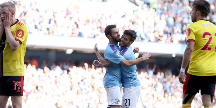 Bernardo Silva (M/l) von Manchester City umarmt David Silva (M/r) nach dem sechsten Treffer gegen Watford. Foto: Maratin Rickett/PA Wire