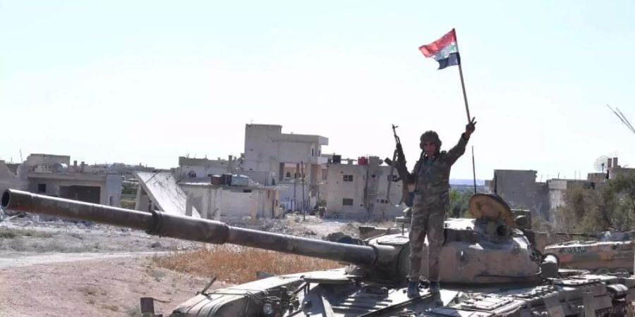 Ein syrischer Soldat zeigt auf einem Panzer das Victory-Zeichen. Foto: Ammar Safarjalani/XinHua