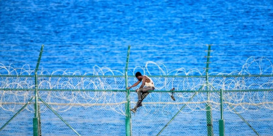 Ein Mann versucht den Grenzzaun nach Ceuta zu überwinden