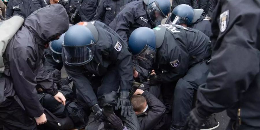 Polizisten lösen eine Sitzblockade von Gegen-Demonstranten auf. Foto: Paul Zinken/dpa