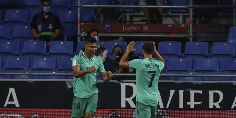 Casemiro (l) klatscht mit Eden Hazard ab. Die beiden Profis von Real Madrid sind positiv auf Corona getestet worden. Foto: Joan Monfort/AP/dpa