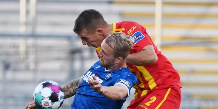Der Karlsruher Philipp Hofmann (l) und Uwe Hünemeier vom KSC kämpfen um den Ball. Foto: Uli Deck/dpa