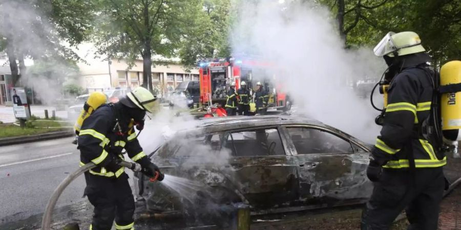 Feuerwehrleute löschen während des G20-Gipfels im Jahr 2017 ein brennendes Auto in Hamburg-Altona. Foto: Bodo Marks/dpa