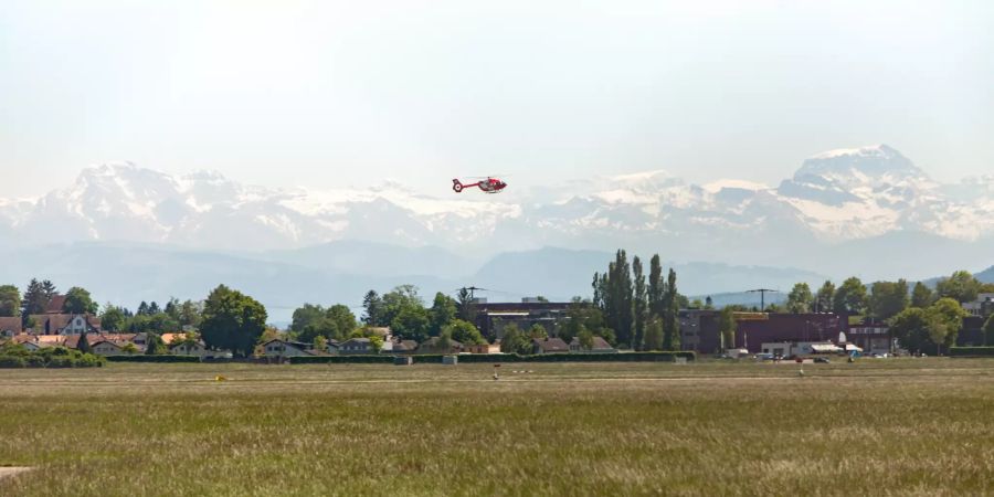 Helikopter im Landeanflug auf den Flugplatz Dübendorf mit Bergpanorama.