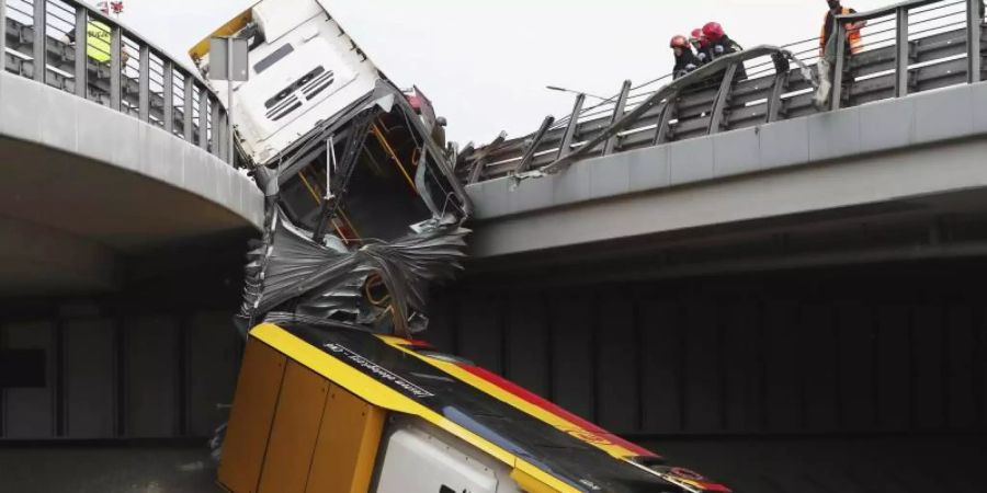 Einsatzkräfte arbeiten an der Unfallstelle. Mindestens ein Mensch ist bei dem Absturz des Linienbusses ums Leben gekommen. Foto: Czarek Sokolowski/AP/dpa