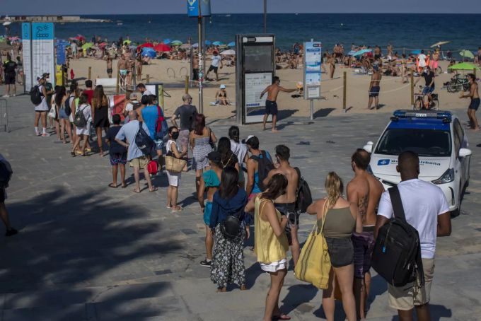 Menschen stehen in Barcelona am 18. Juli Schlange, nachdem der Strand aufgrund von Überfüllung durch die Behörden geschlossen wurde. Coronavirus Spanien zweite Welle