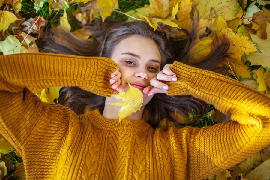 frau mit herbstblatt in den händen, herbstboden