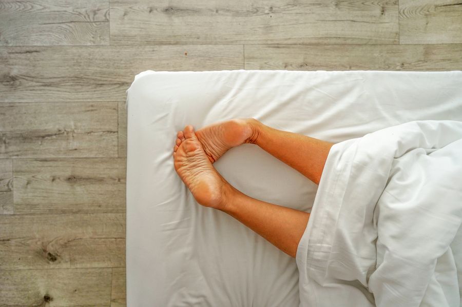 Beine und Füsse einer Person, die im Bett liegt