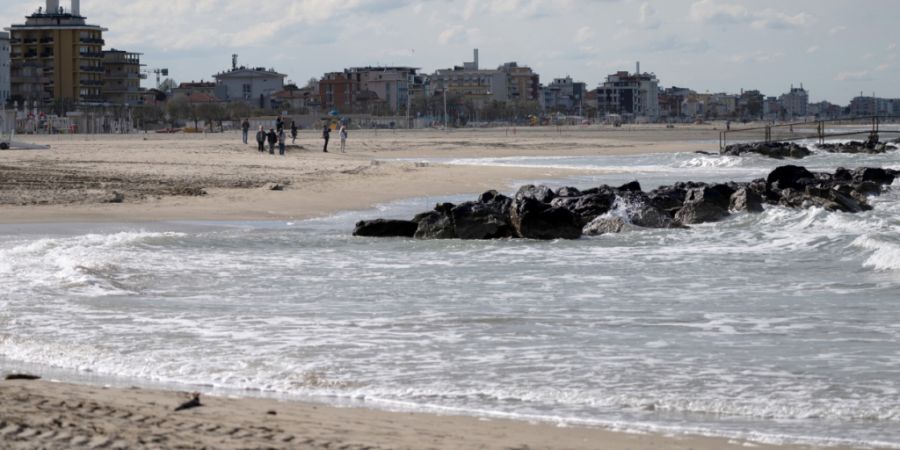 ARCHIV - Menschen gehen an einem Strandstück in Rimini entlang. Foto: Marijan Murat/dpa